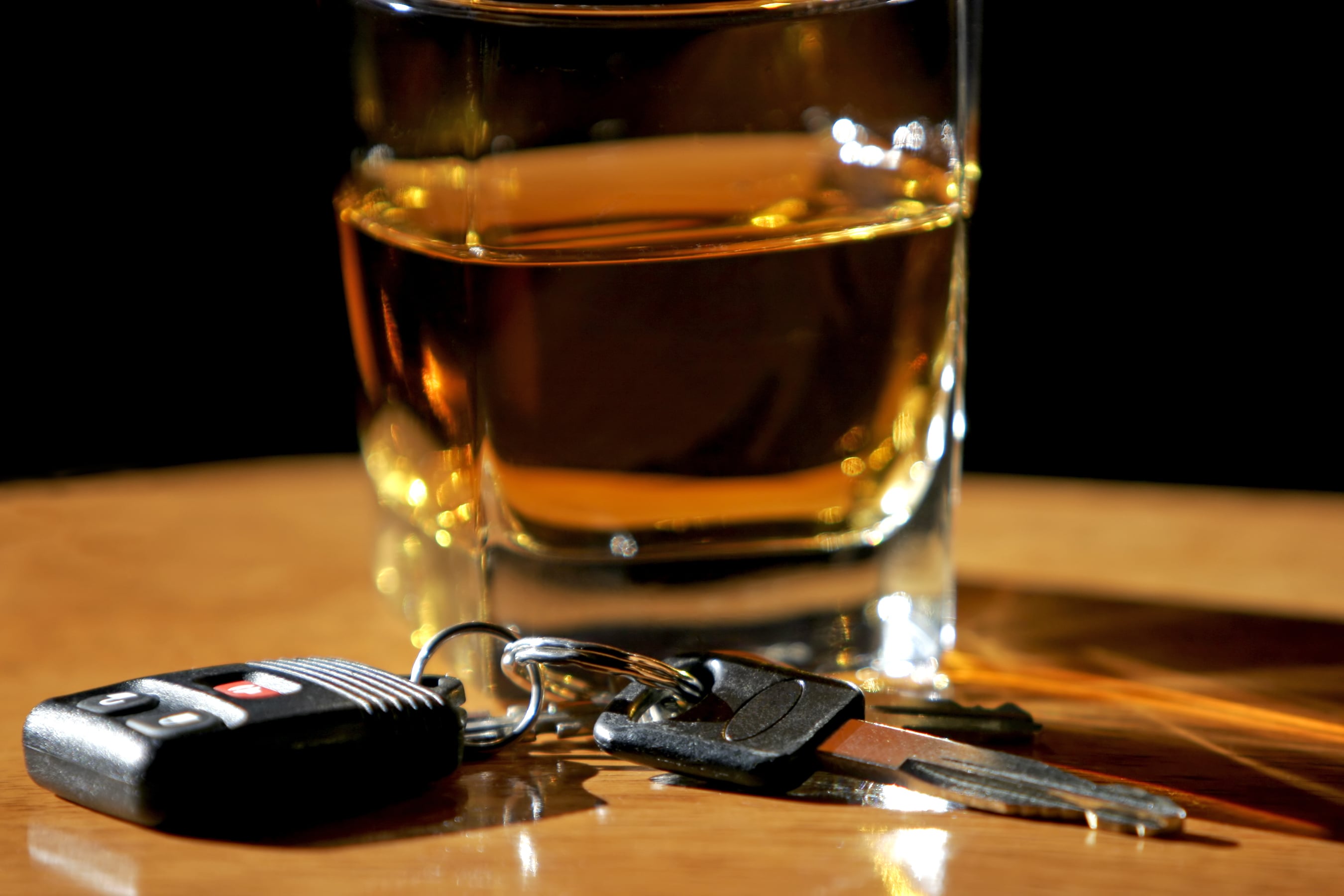 Glass of alcohol next to car keys. 